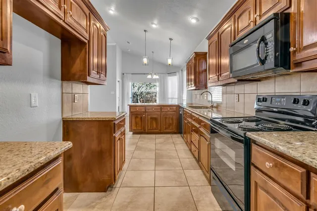 a kitchen with stainless steel appliances granite countertop a stove a sink and a microwave