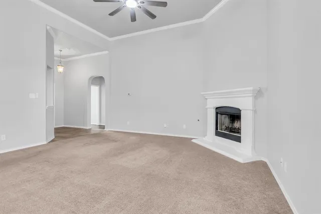 an empty room with a fireplace and chandelier fan