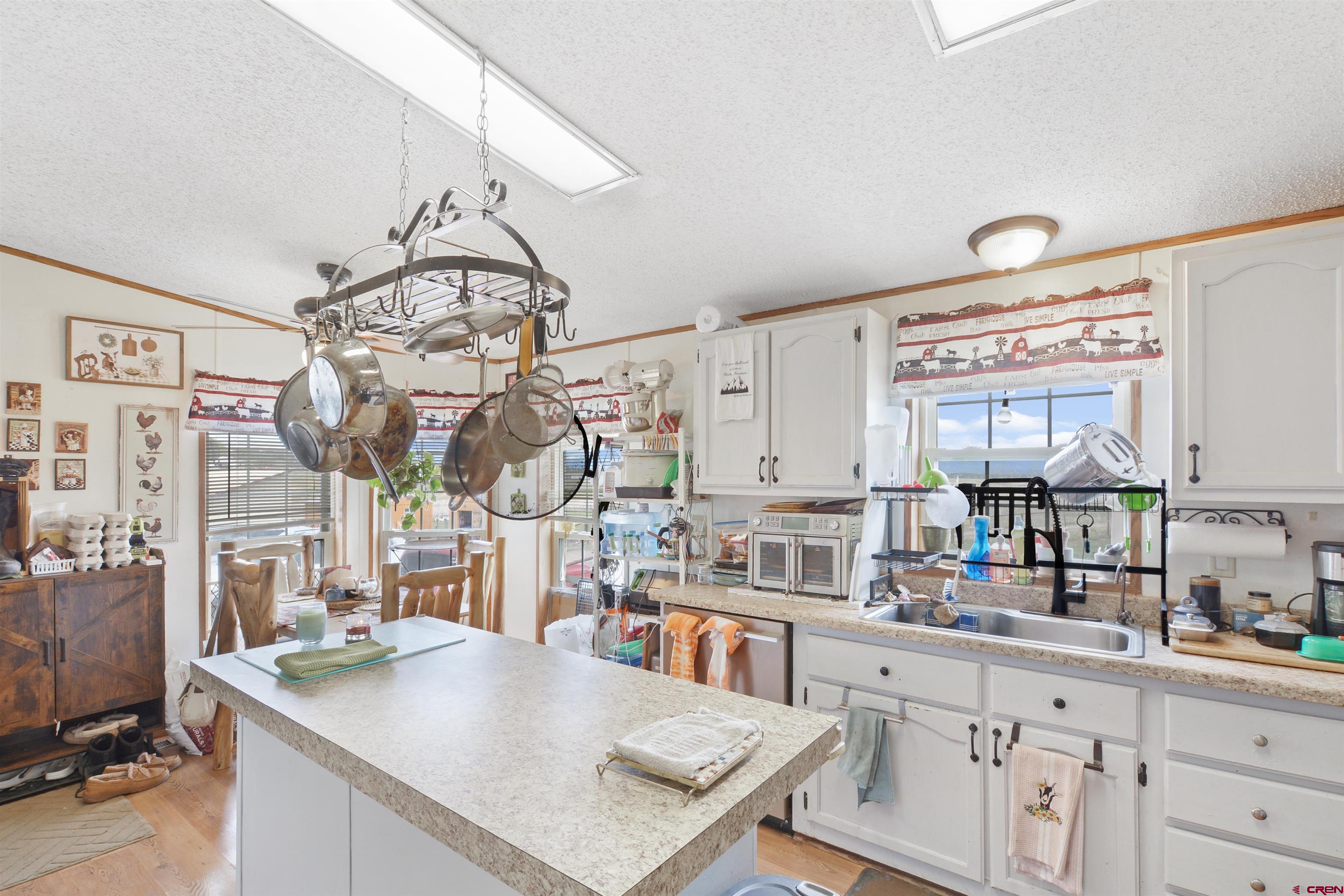 3519 County Road 311 Ignacio, CO 81137 - Photo 9 of 22 a kitchen with stainless steel appliances granite countertop a sink dishwasher and white cabinets with wooden floor