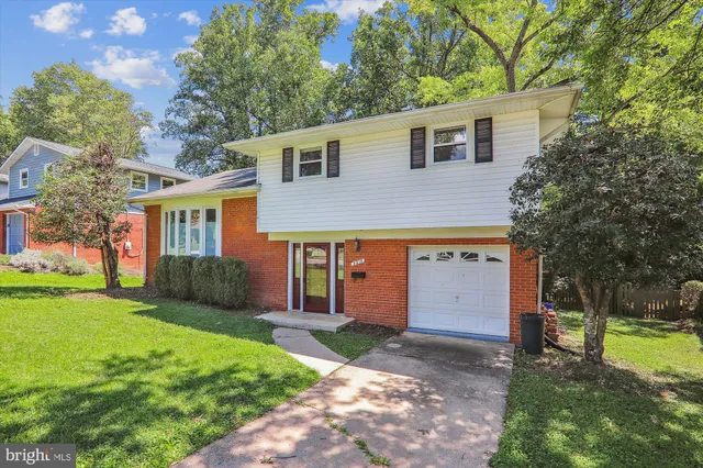 a front view of a house with a yard and trees