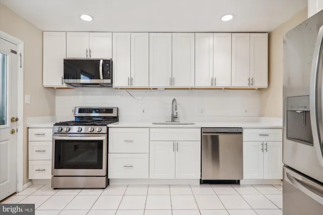 a kitchen with white cabinets and stainless steel appliances