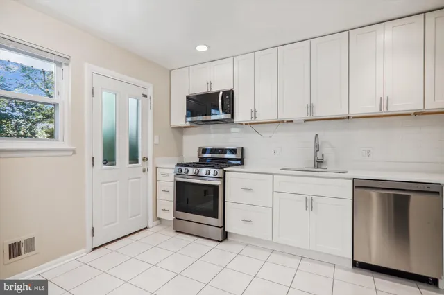 a kitchen with white cabinets and appliances