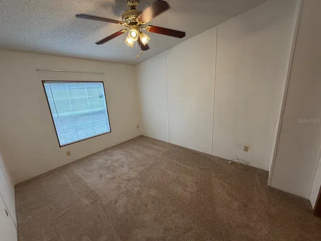 en empty room with windows and fan