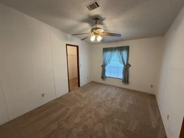 en empty room with ceiling fan and window
