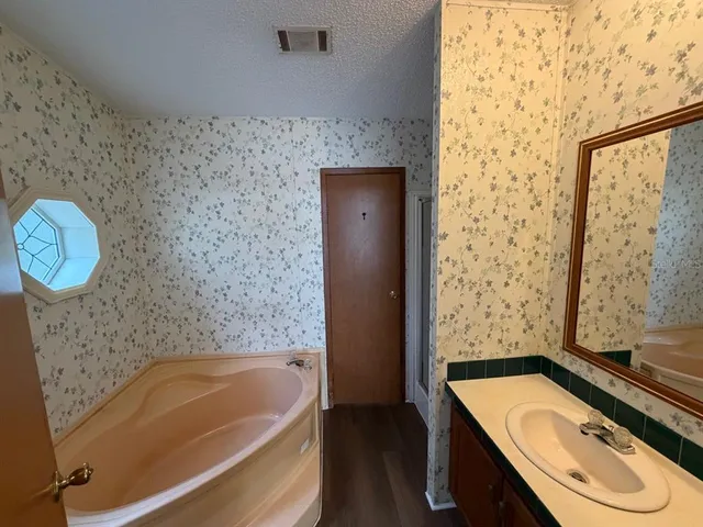 a bathroom with a tub sink and mirror