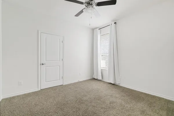 an empty room with a ceiling fan and carpet