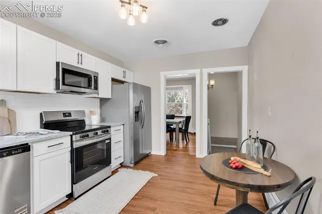 a kitchen with stainless steel appliances kitchen island granite countertop a stove a sink dishwasher a dining table and chairs with wooden floor