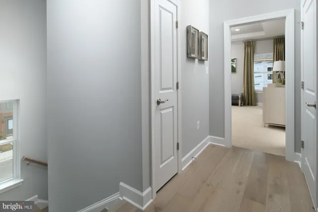 a view of a hallway with wooden floor and a bathroom