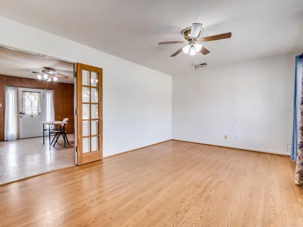a view of an empty room with window and wooden floor