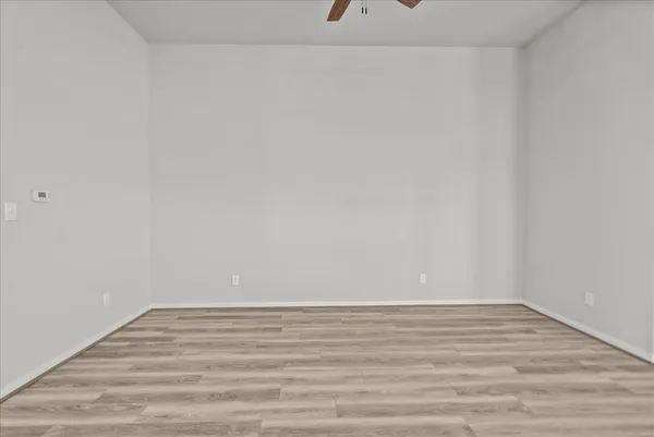 an empty room with a window and a ceiling fan