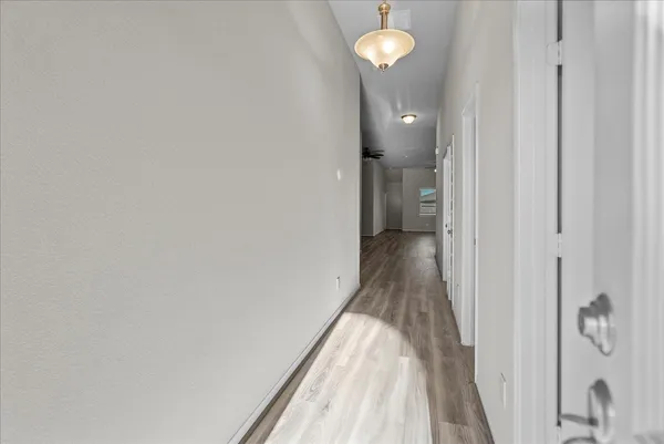 a view of a hallway with wooden floor and a bathroom