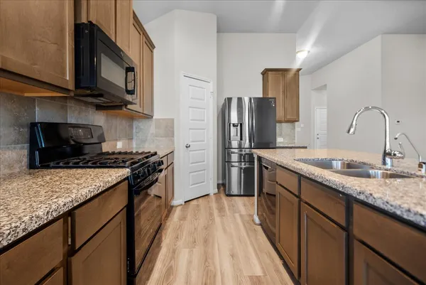 a kitchen with stainless steel appliances granite countertop a sink stove microwave refrigerator and cabinets