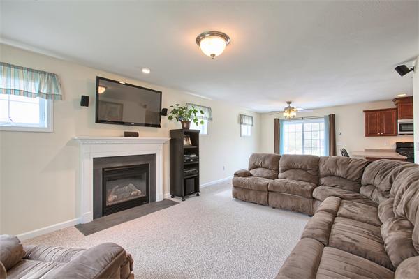 92 Scobie Pond Road Derry, NH 03038 - Photo 9 of 30 a living room with furniture a flat screen tv and a fireplace