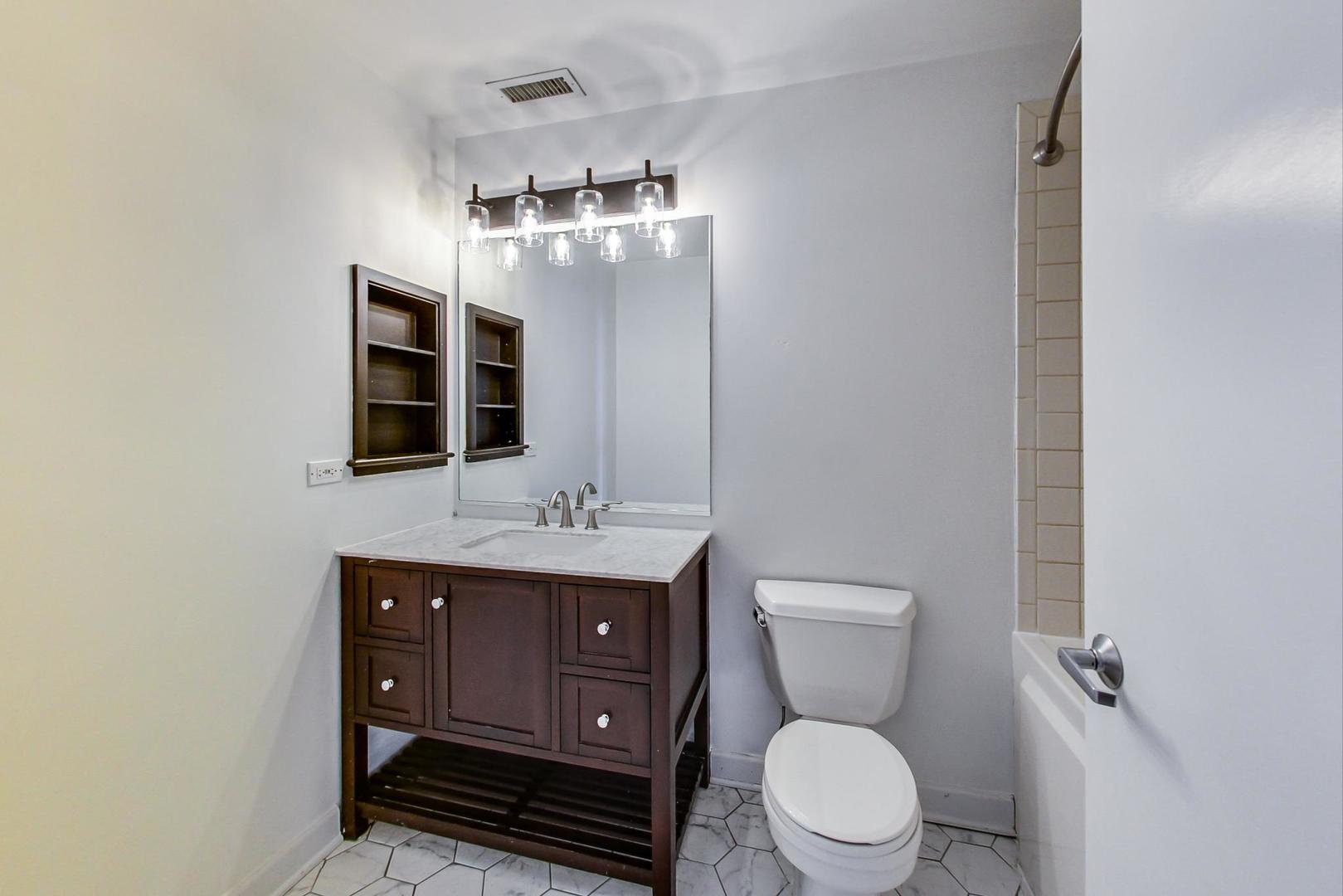 1301 West Madison Street, Unit 511 Chicago, IL 60607 - Photo 17 of 24 a spacious bathroom with a toilet a sink and mirror