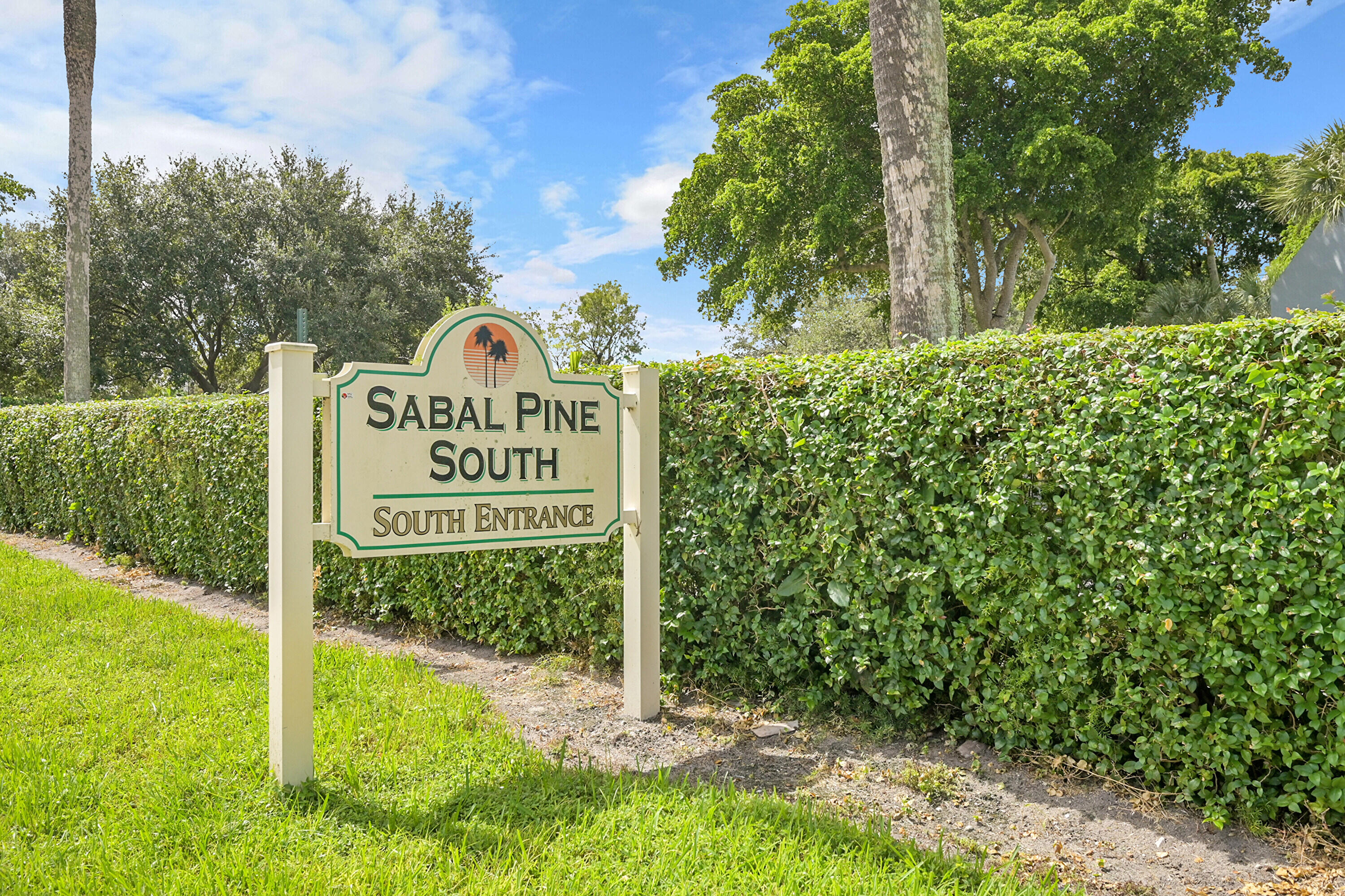 a sign of golf club on a wall under a large tree