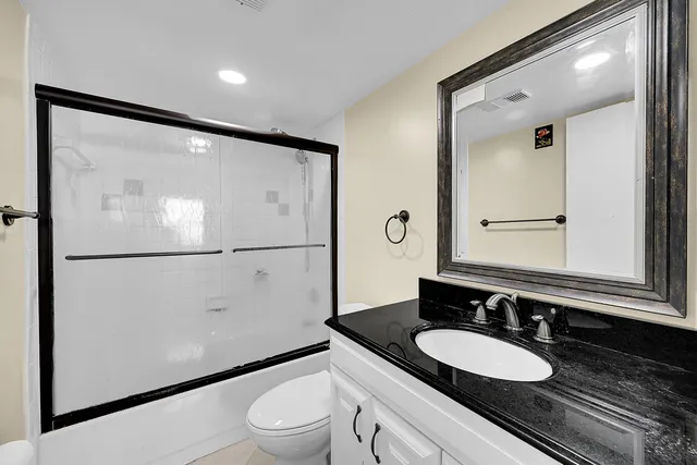 a bathroom with a granite countertop sink mirror vanity and toilet