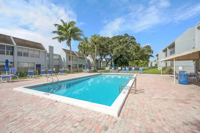 a view of swimming pool with outdoor seating and house in the background