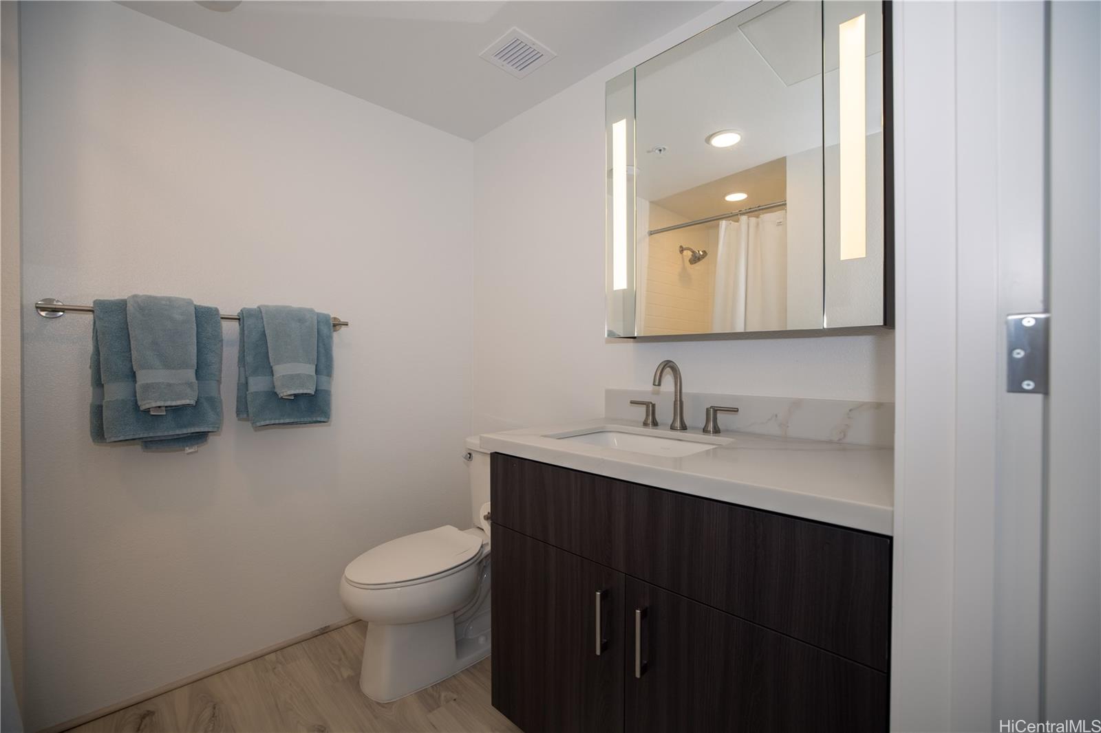 615 Keawe Street, Unit 2408 Honolulu, HI 96813 - Photo 12 of 16 a bathroom with a granite countertop sink a toilet and a mirror
