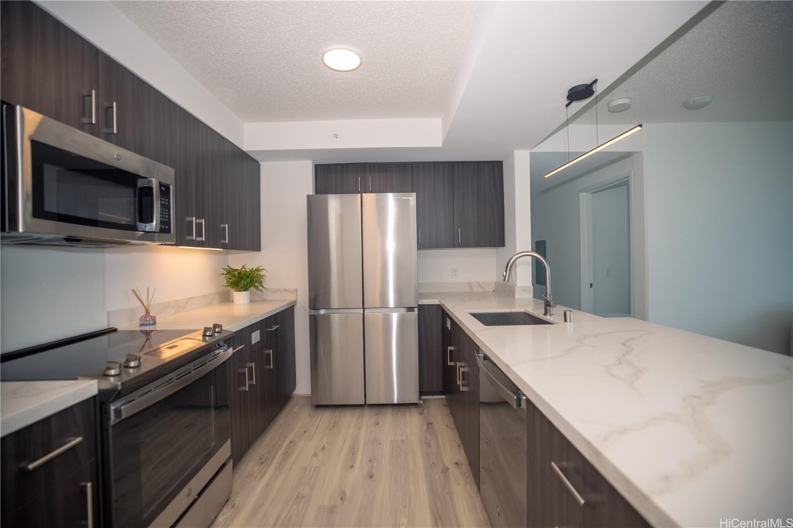 615 Keawe Street, Unit 2408 Honolulu, HI 96813 - Photo 2 of 16 a kitchen with granite countertop a refrigerator stove and microwave
