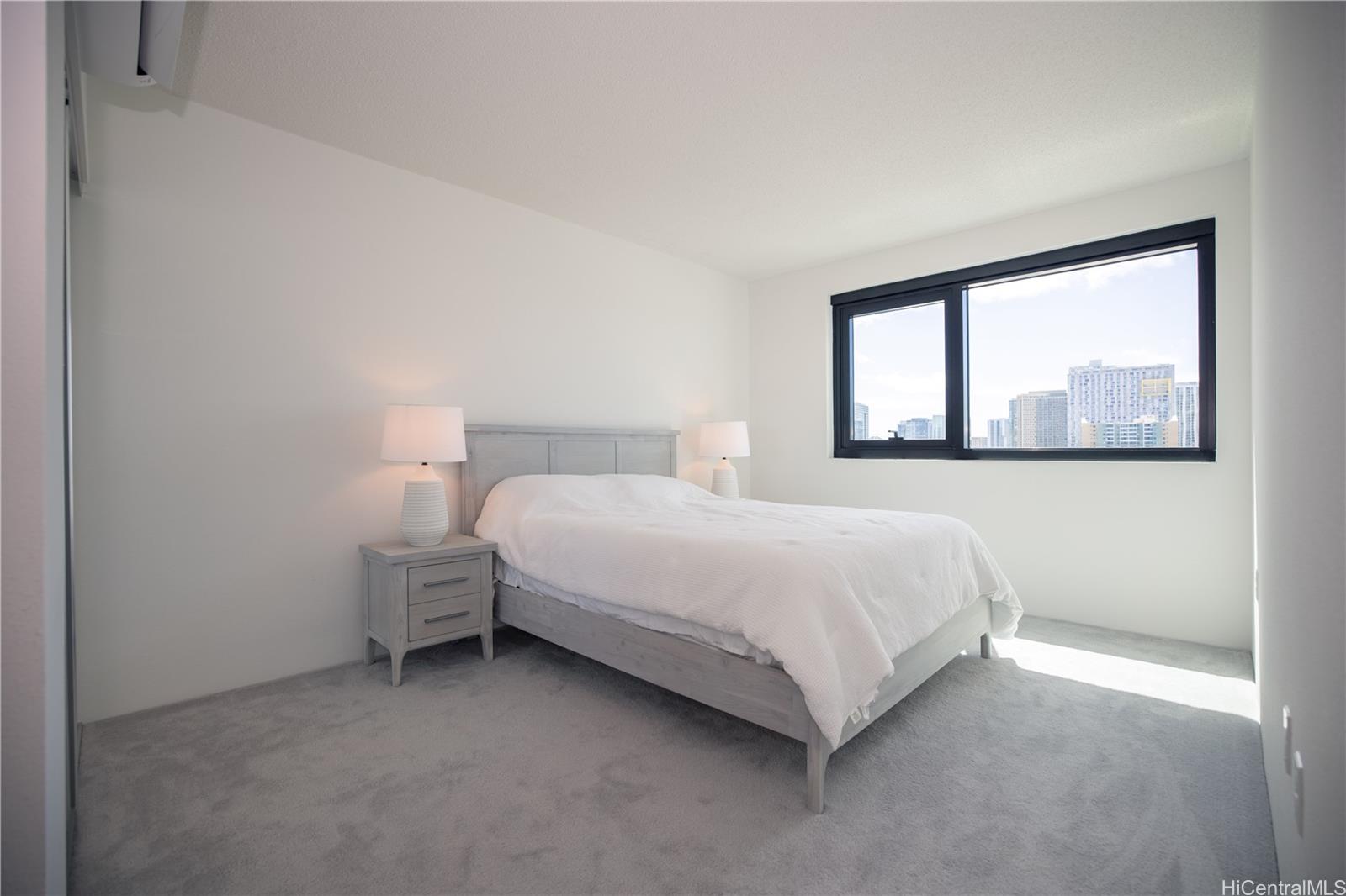 615 Keawe Street, Unit 2408 Honolulu, HI 96813 - Photo 8 of 16 a large bed sitting in a bedroom next to a window