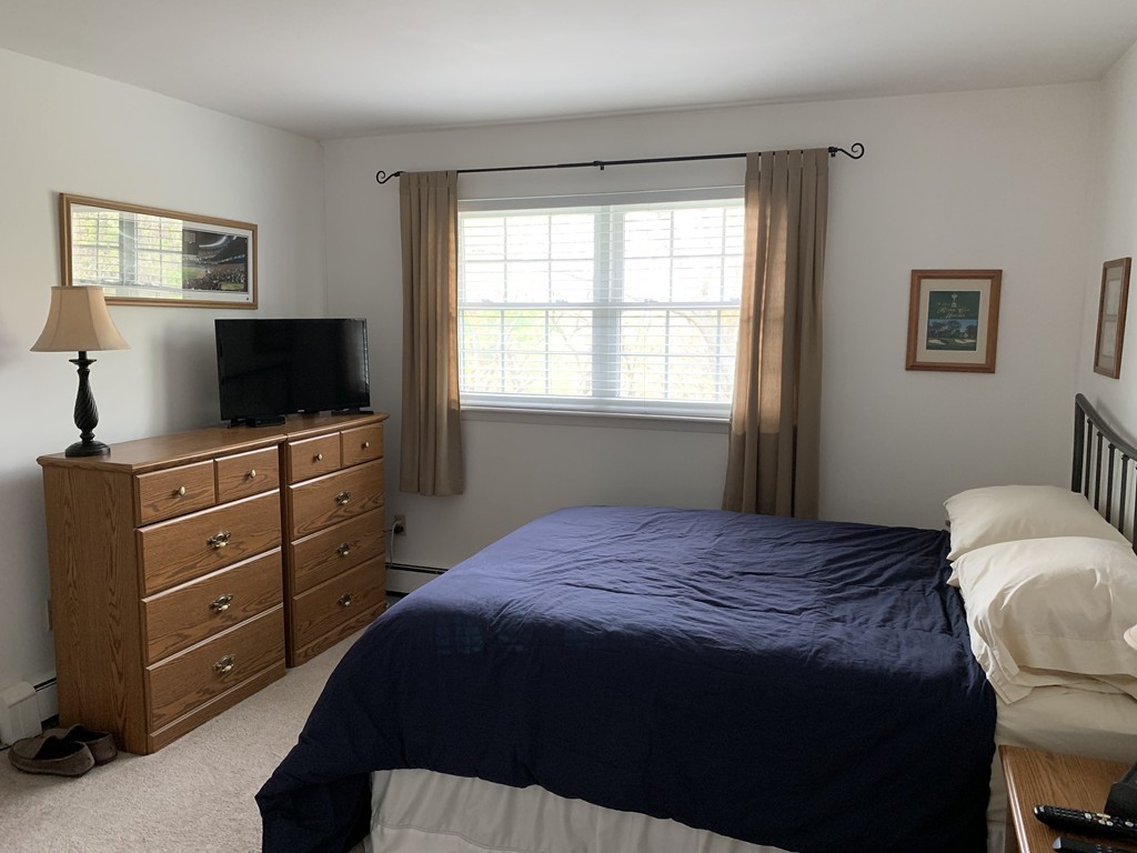 64 Jacqueline Road, Unit 12 Waltham, MA 02452 - Photo 15 of 16 a bedroom with a bed and a flat tv screen on dresser