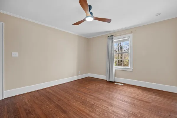 a view of an empty room with wooden floor and a window