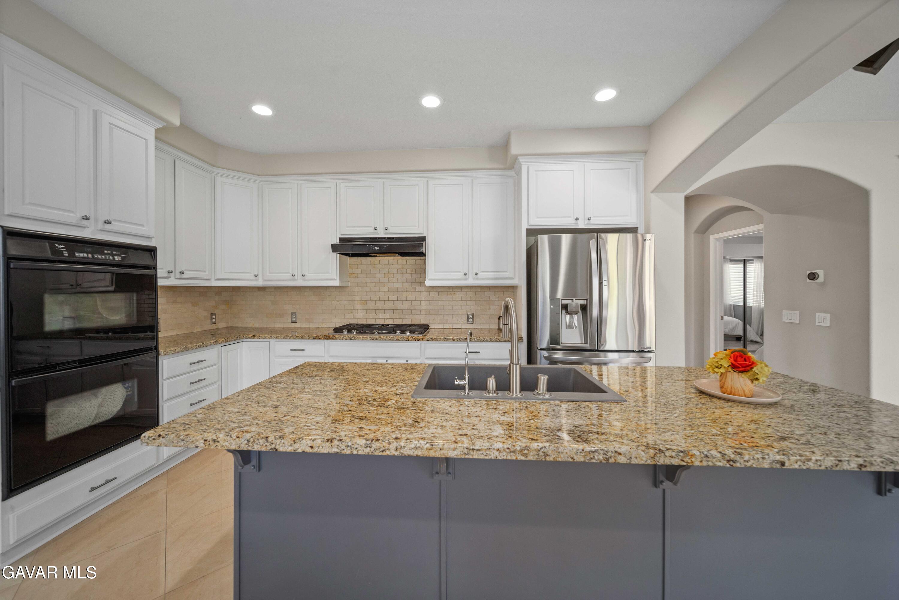 26505 Thackery Lane Stevenson Ranch, CA 91381 - Photo 23 of 63 a kitchen with kitchen island granite countertop counter top space cabinets and stainless steel appliances
