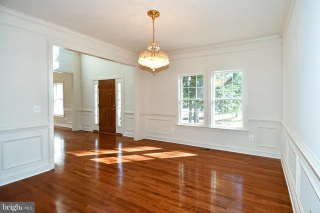 an empty room with wooden floor cabinet and windows