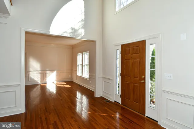a kitchen with granite countertop a stove a sink a refrigerator and white cabinets with wooden floor