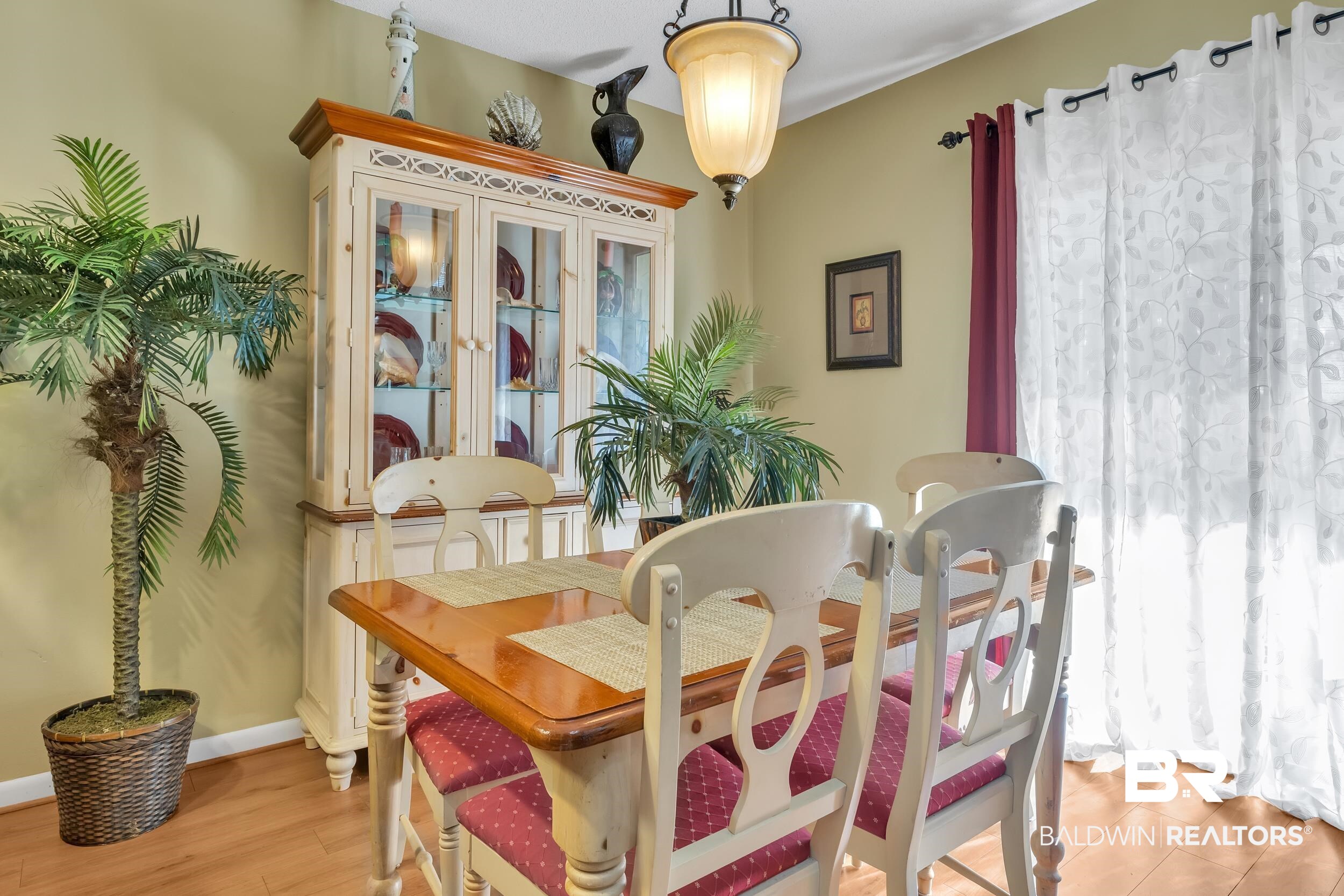 3256 Loop Road, Unit 2 Orange Beach, AL 36561 - Photo 13 of 25 Dining area featuring wood-finish flooring, a decorative hutch with glass-front cabinets, and a chandelier with frosted glass