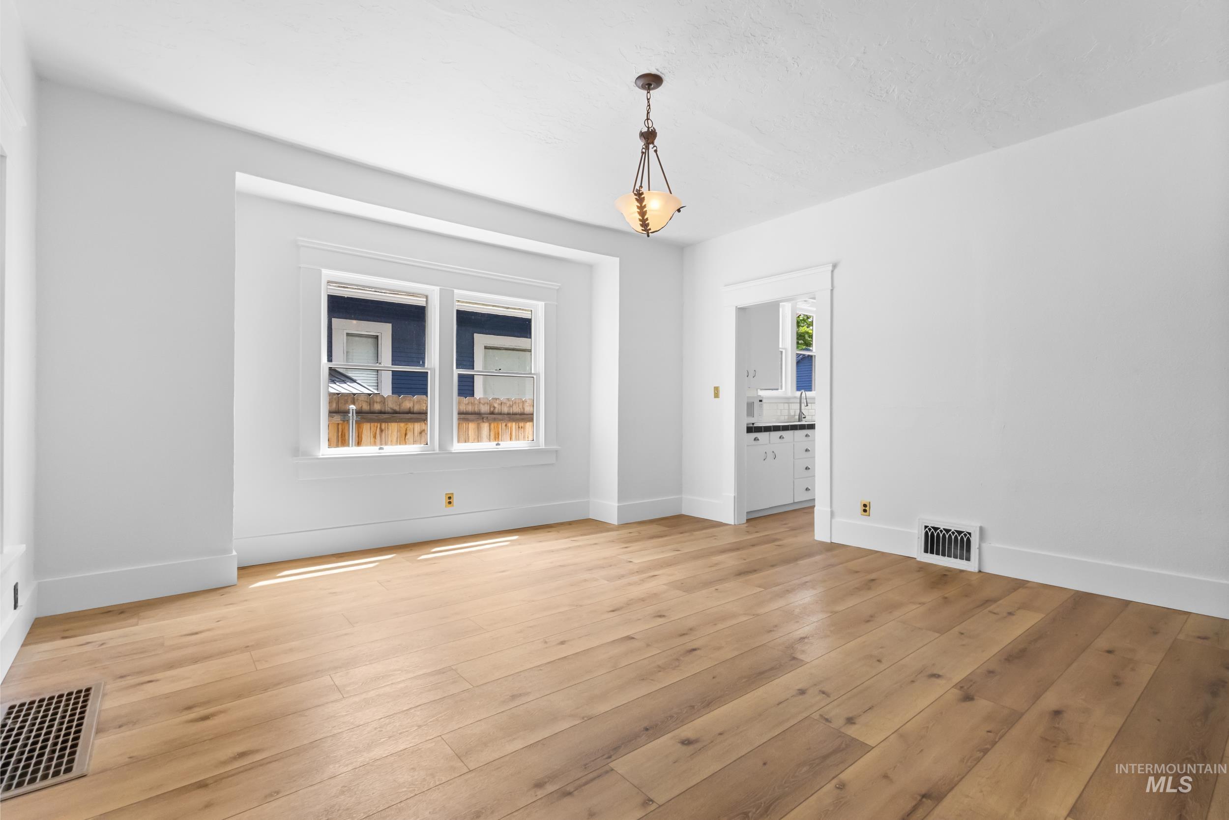 2119 West Brumback Street Boise, ID 83702 - Photo 7 of 30 Spacious interior room featuring light wood-finish flooring, white painted walls, and a decorative pendant light fixture