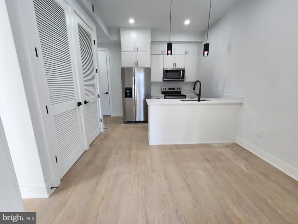 a view of kitchen with stainless steel appliances refrigerator stove microwave and cabinets