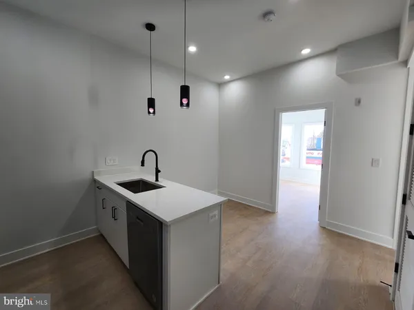 a kitchen with a sink and wooden floor