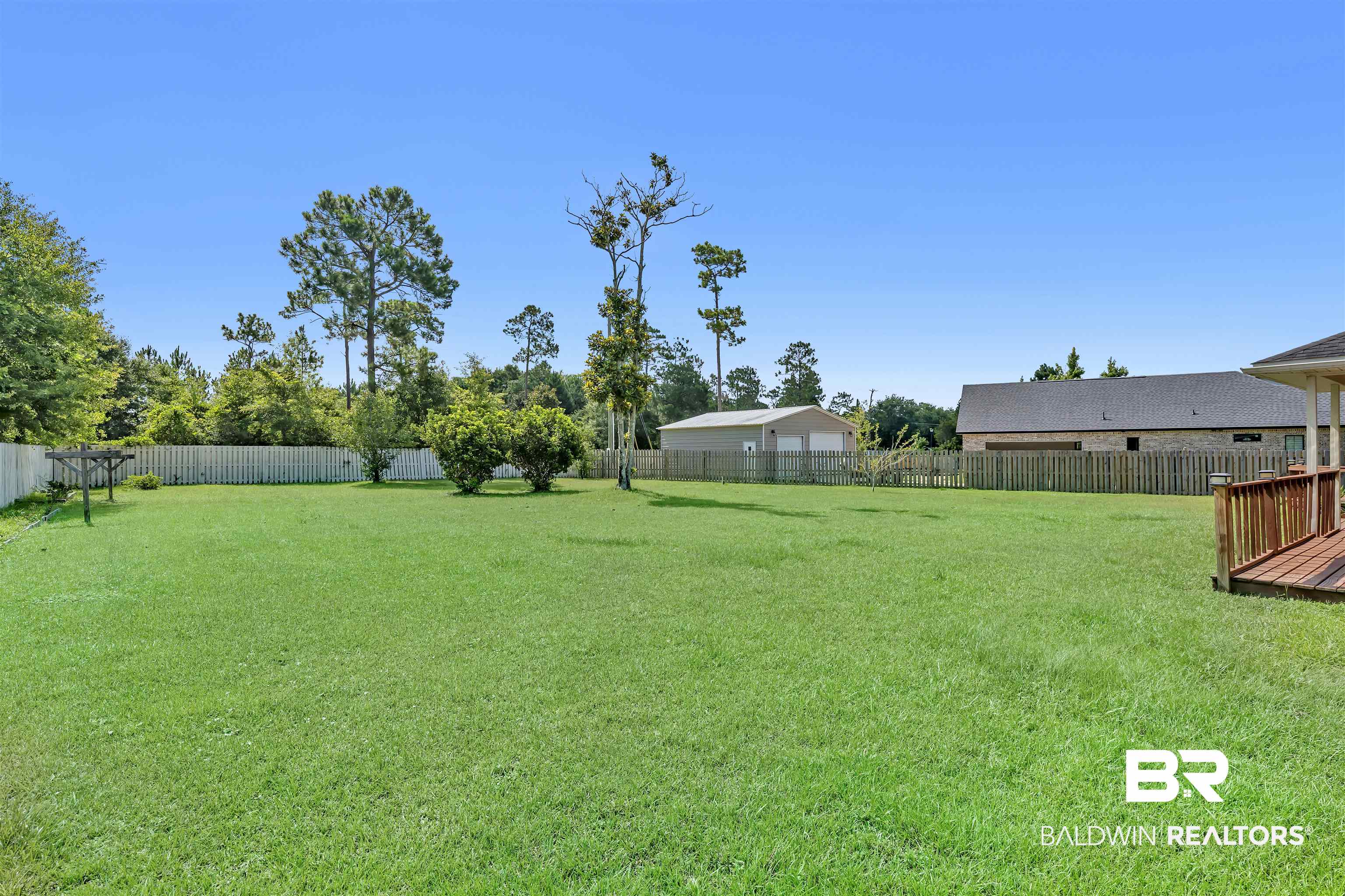 10147 Lyttleton Loop Lillian, AL 36549 - Photo 8 of 29 Expansive fenced yard featuring a detached garage, established trees, and a wooden deck
