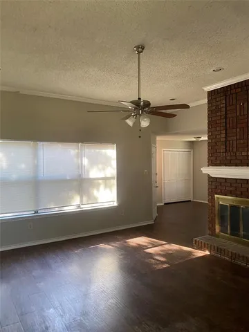 a view of an empty room with window fireplace and wooden floor