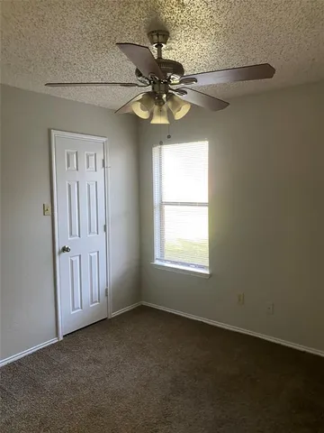an empty room with a window and a chandelier fan