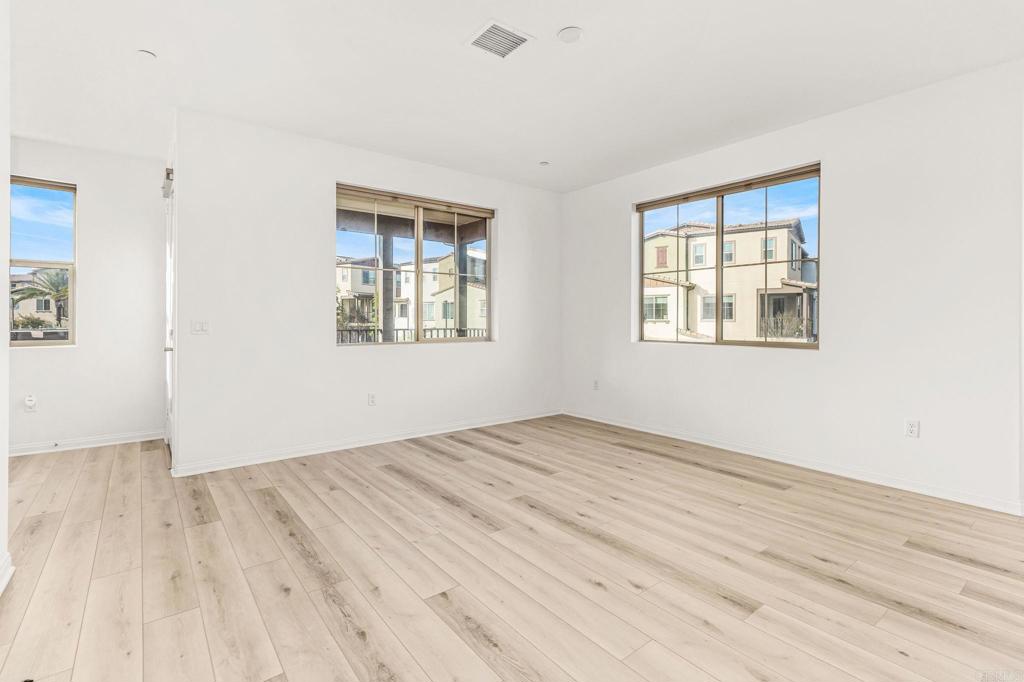1609 Holly Leaf Way Oceanside, CA 92056 - Photo 10 of 26 an empty room with wooden floor and windows