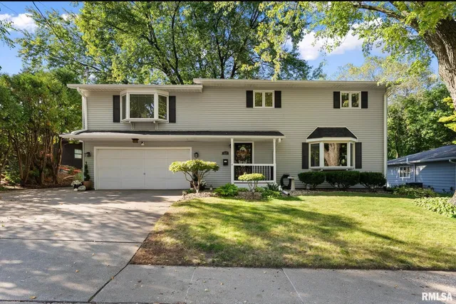 a front view of house with yard and trees in the background