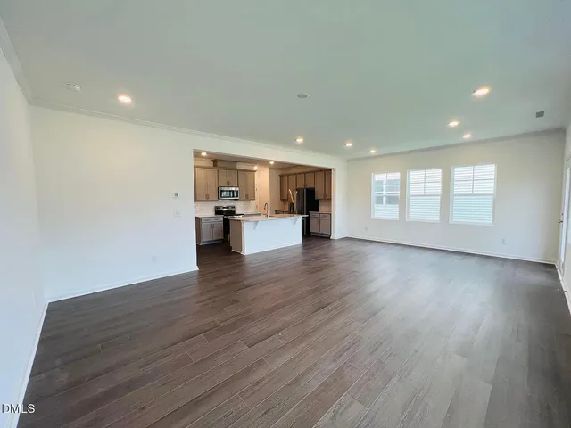 a view of empty room with kitchen and window