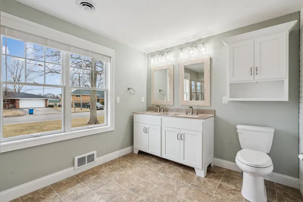 a bathroom with a granite countertop toilet a sink and a large mirror