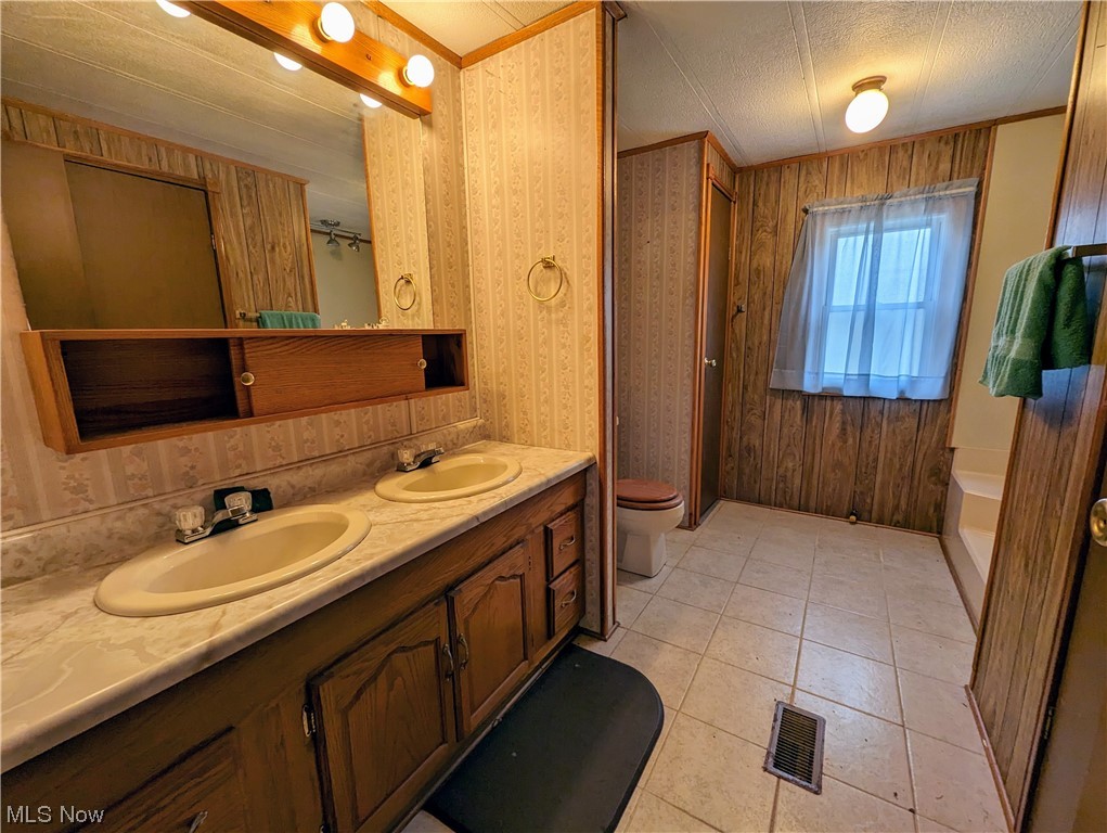 10267 Cable Line Road Newton Falls, OH 44444 - Photo 15 of 33 Bathroom featuring toilet, a textured ceiling, tile flooring, wooden walls, and double sink vanity