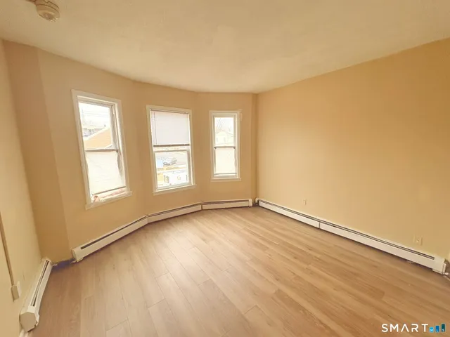 a view of an empty room with a window and wooden floor