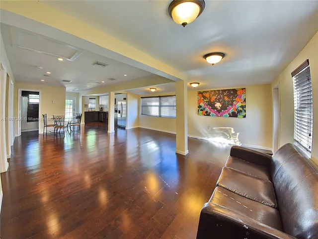 a living room with couches and kitchen view with wooden floor