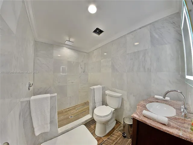 a bathroom with a granite countertop sink toilet a mirror and shower