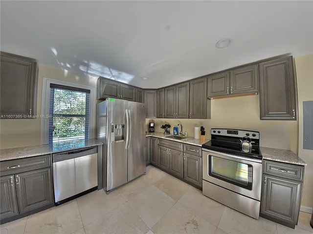 a kitchen with stainless steel appliances granite countertop a refrigerator stove and sink