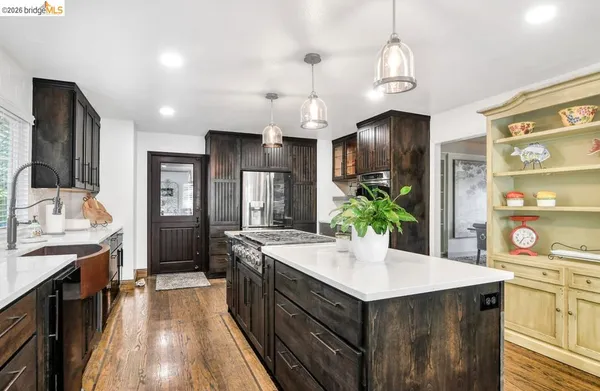 a kitchen with stainless steel appliances kitchen island granite countertop a refrigerator a stove oven and white cabinets with wooden floor