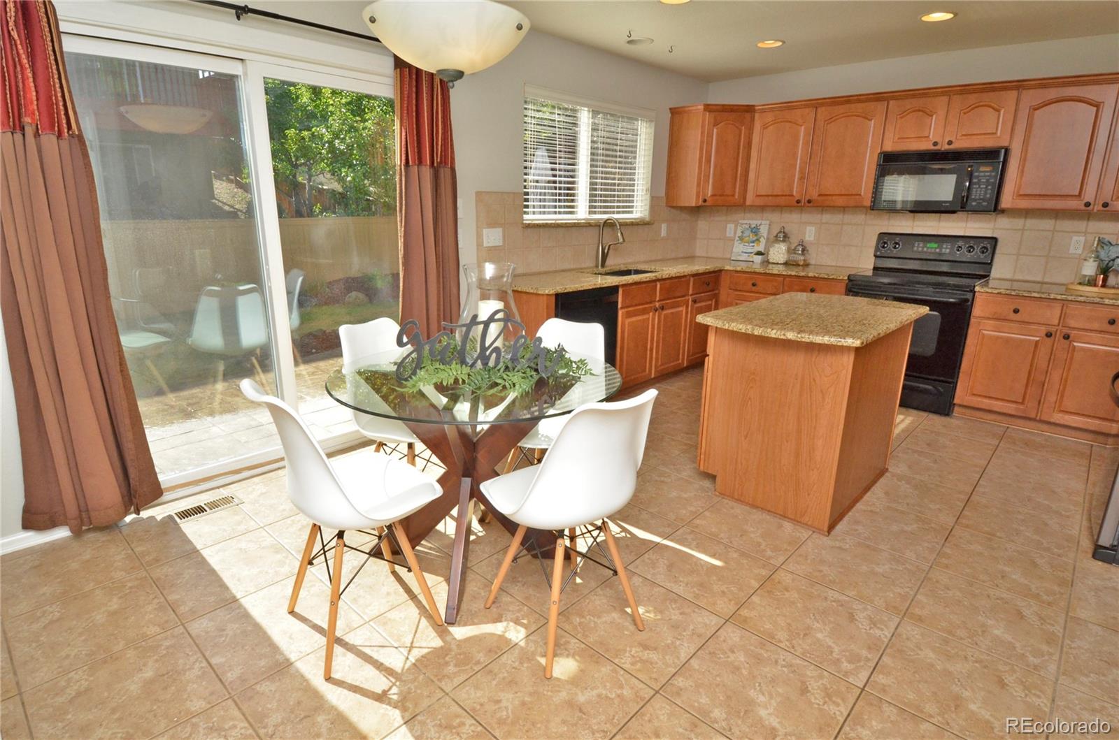 10699 Wynspire Way Highlands Ranch, CO 80130 - Photo 13 of 40 a kitchen with stainless steel appliances granite countertop a stove a sink a microwave a dining table and chairs