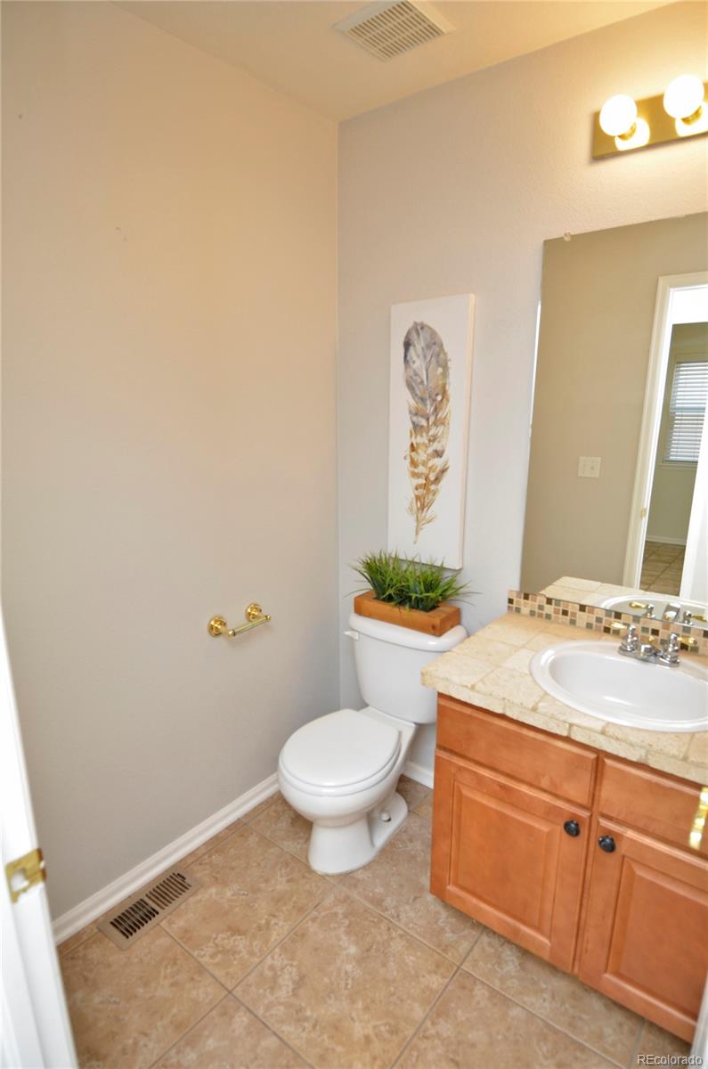 10699 Wynspire Way Highlands Ranch, CO 80130 - Photo 19 of 40 a bathroom with a granite countertop toilet a sink and a mirror