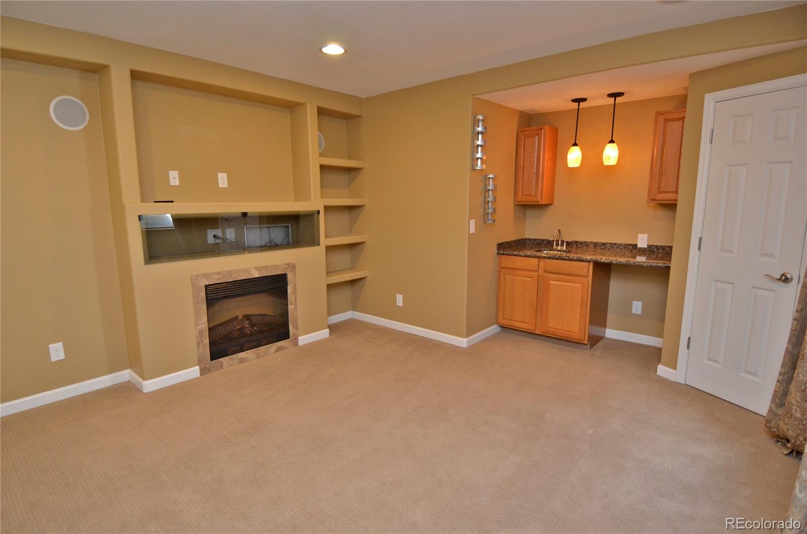 10699 Wynspire Way Highlands Ranch, CO 80130 - Photo 34 of 40 an empty room with kitchen view and a fireplace
