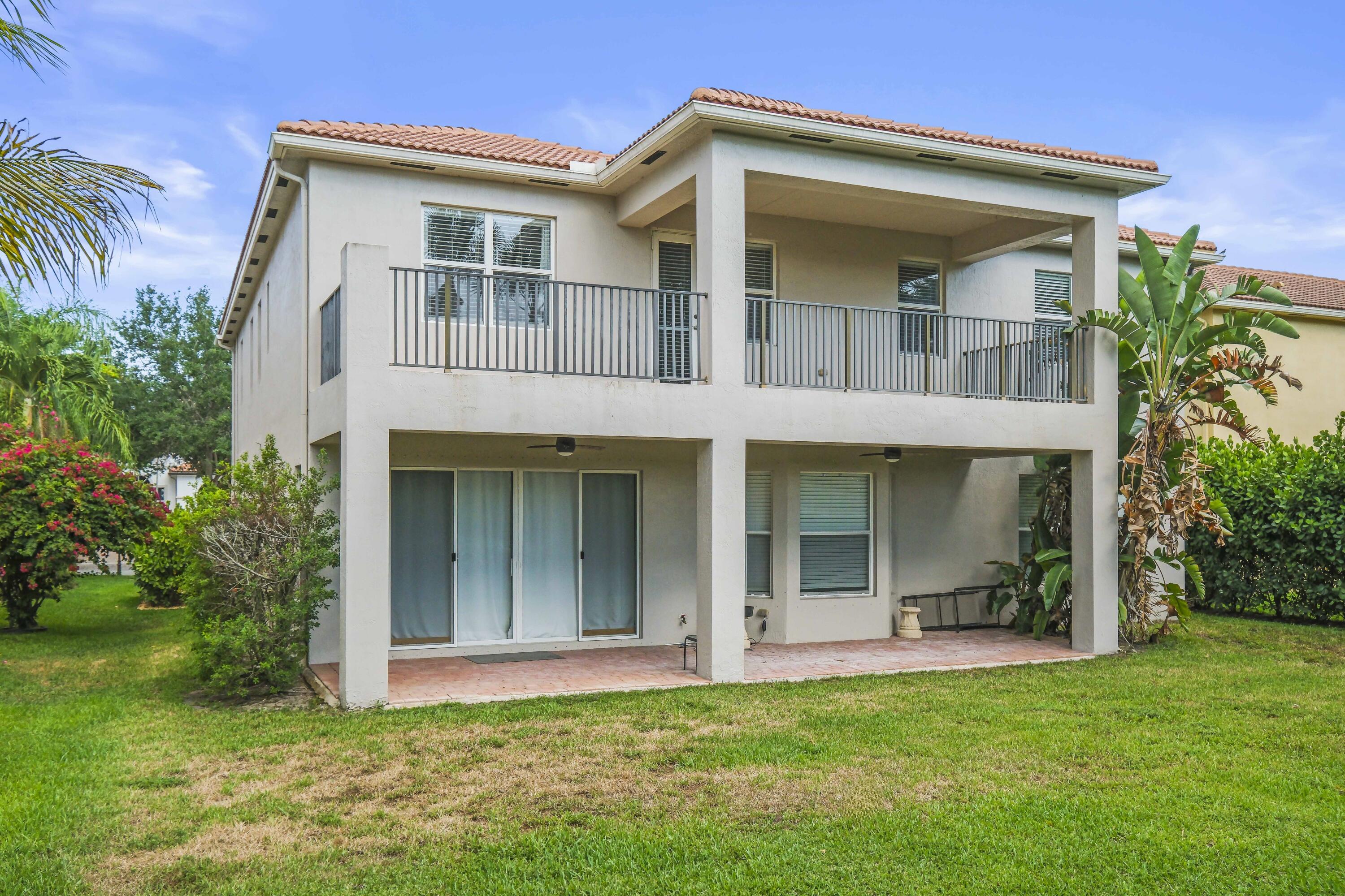 8620 Cobblestone Point Circle Boynton Beach, FL 33472 - Photo 39 of 42 a view of a white house with a large windows and a yard with plants